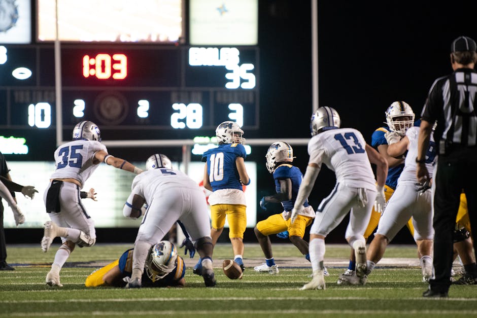 Athletes in action during a thrilling late-night American football match in a stadium.