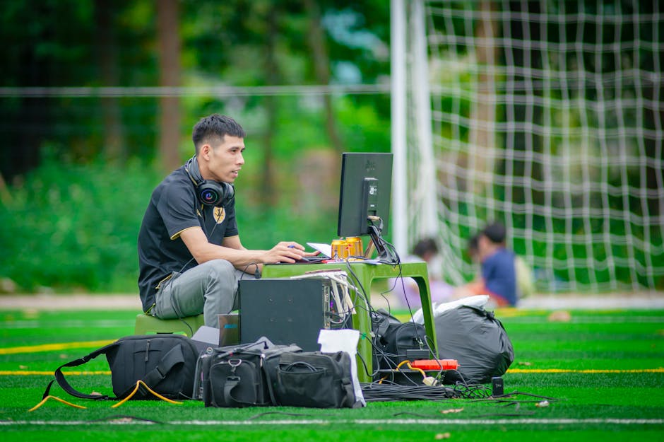 Man working at a computer setup on a football field in Hanoi, Vietnam.